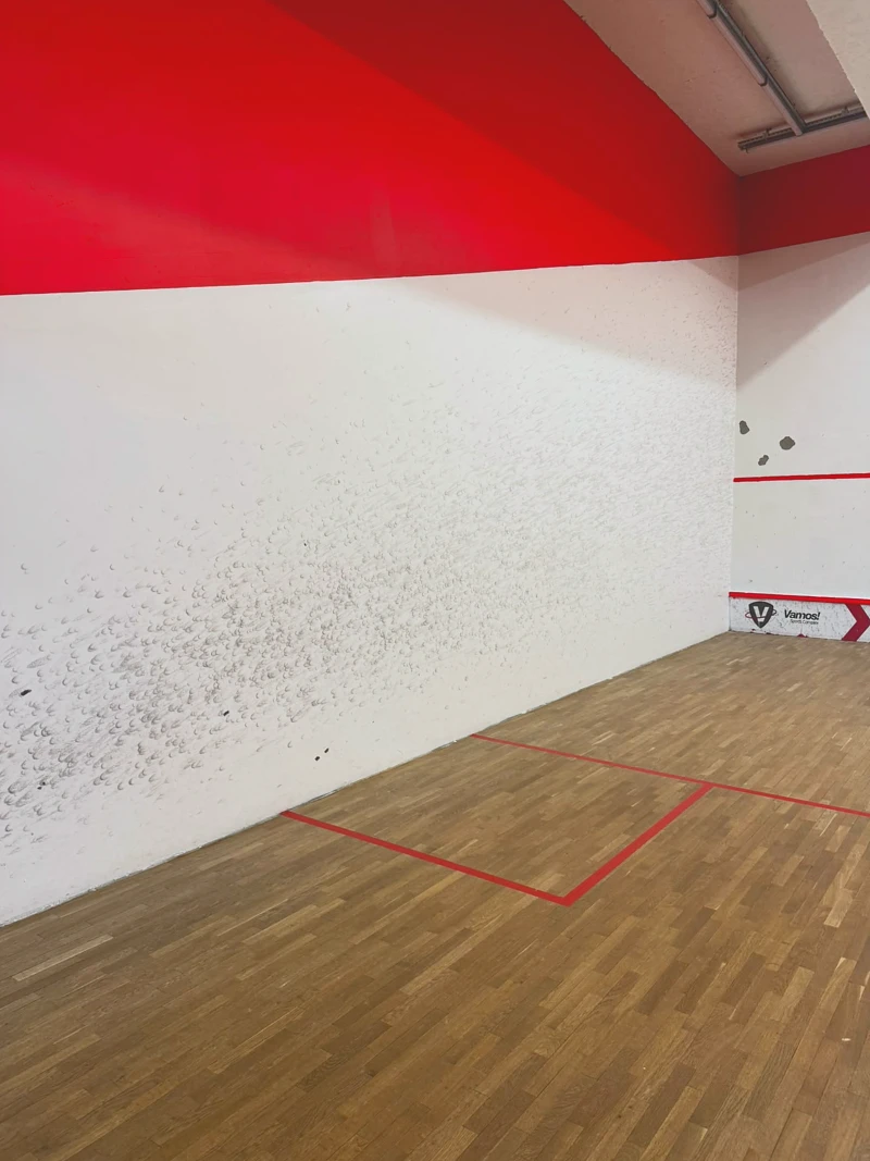 Kırmızı bantlı squash kortu ve Vamos logosu